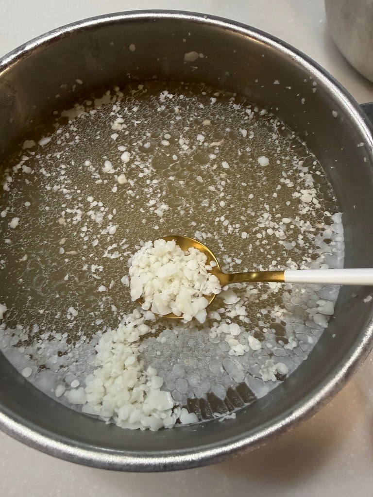 Skimming off solid white beef tallow from chilled broth with a spoon