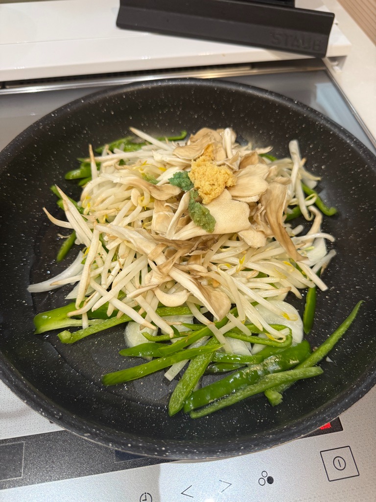 Crisp bell peppers, bean sprouts, onions, maitake mushrooms, and ginger in the pan